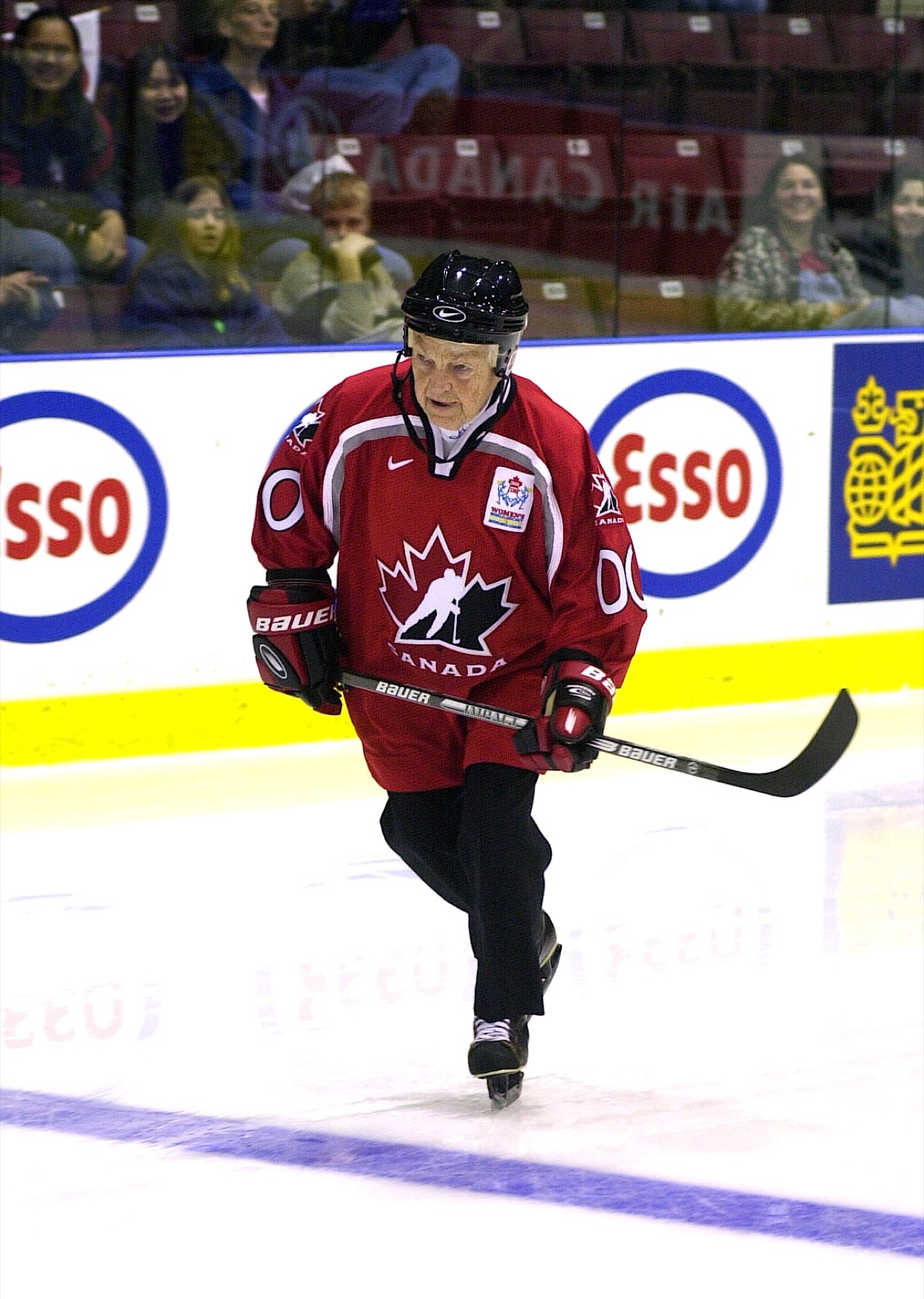 Hazel McCallion playing hockey, skating with the puck in a red jersey.