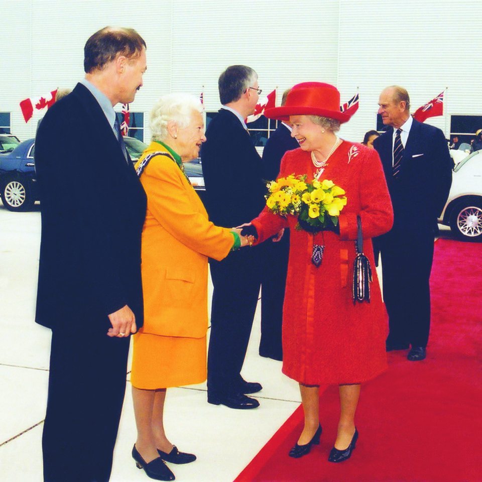 Hazel McCallion, in her mayoral chain of office, shaking hands with Queen Elizabeth II on a red carpet.